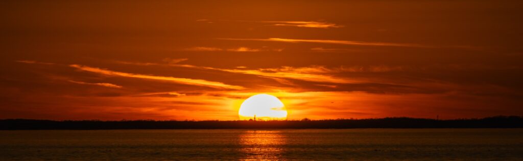 The sun sets over a body of water.