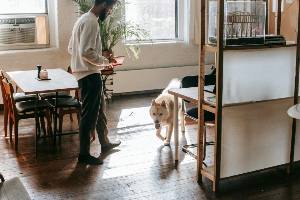 A young man leisurely spending time with his Akita dog in a modern apartment setting.