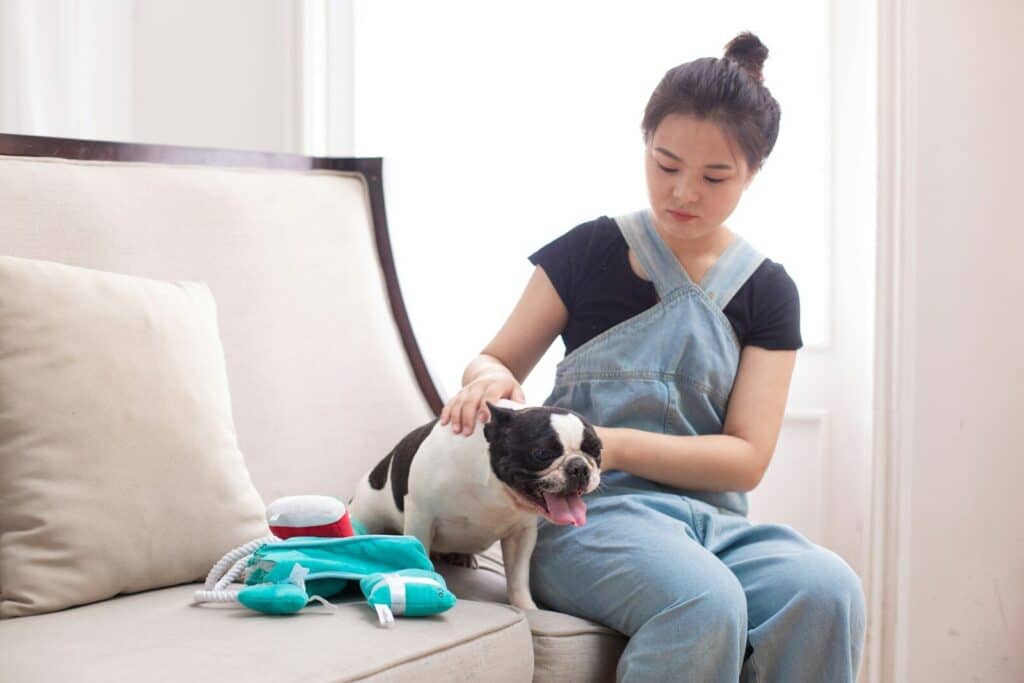A woman pets her dog on a couch.