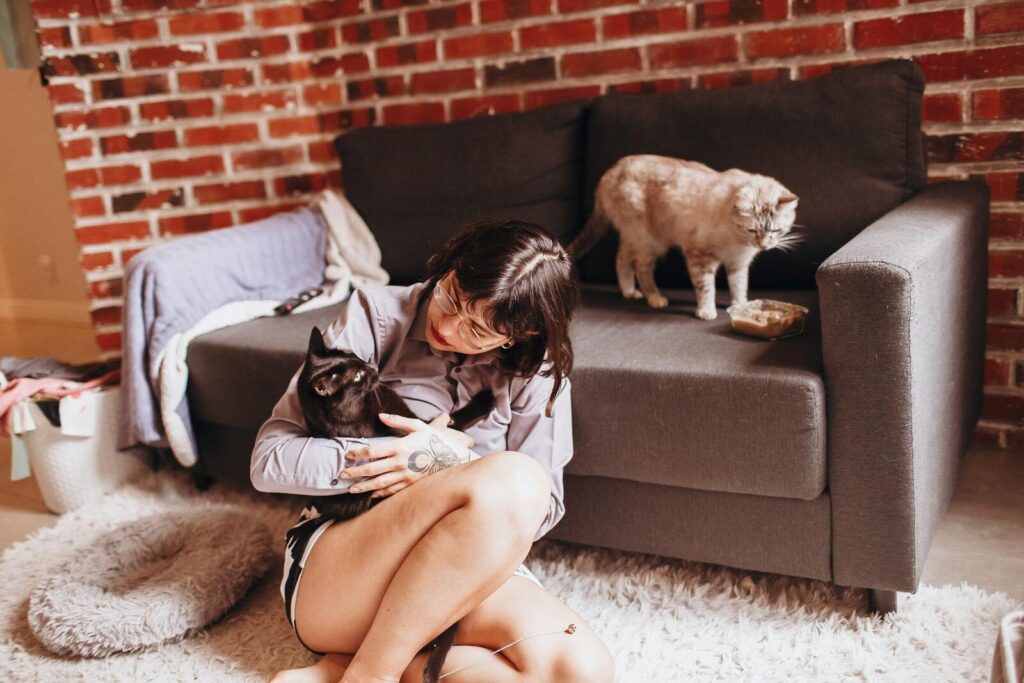 A woman enjoys a quiet moment with her cats in a comfortable living room.